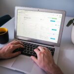 person using macbook air on white table