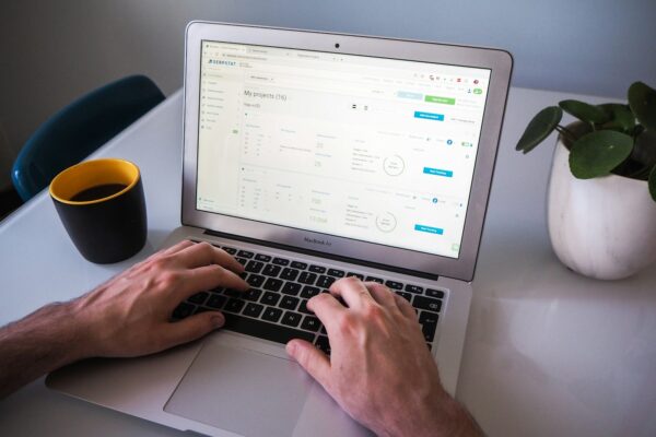 person using macbook air on white table