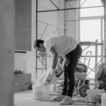 A construction worker pours materials inside a building under renovation.