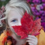 girl holding red maple leaf