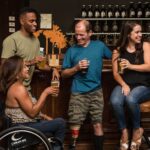 Friends with disabilities enjoying craft beers and socializing in a cozy bar.