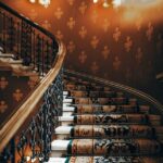 A beautifully detailed vintage staircase with ornate iron handrails and rich patterned carpet.