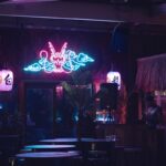 A restaurant with a neon sign above the tables