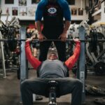 man in black crew neck t-shirt and gray pants sitting on black and red bench